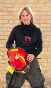 author in bunker pants, holding a red fire helmet
